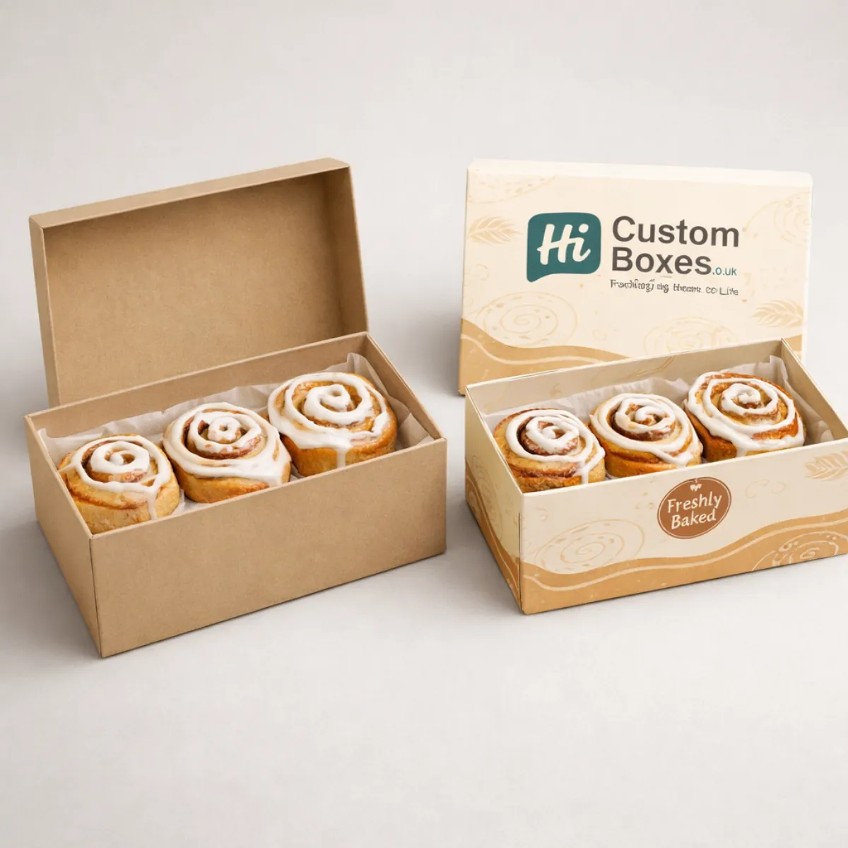 Two sturdy wholesale boxes with lids, displaying four large, spiralled cinnamon rolls with thick white cream frosting. class=
